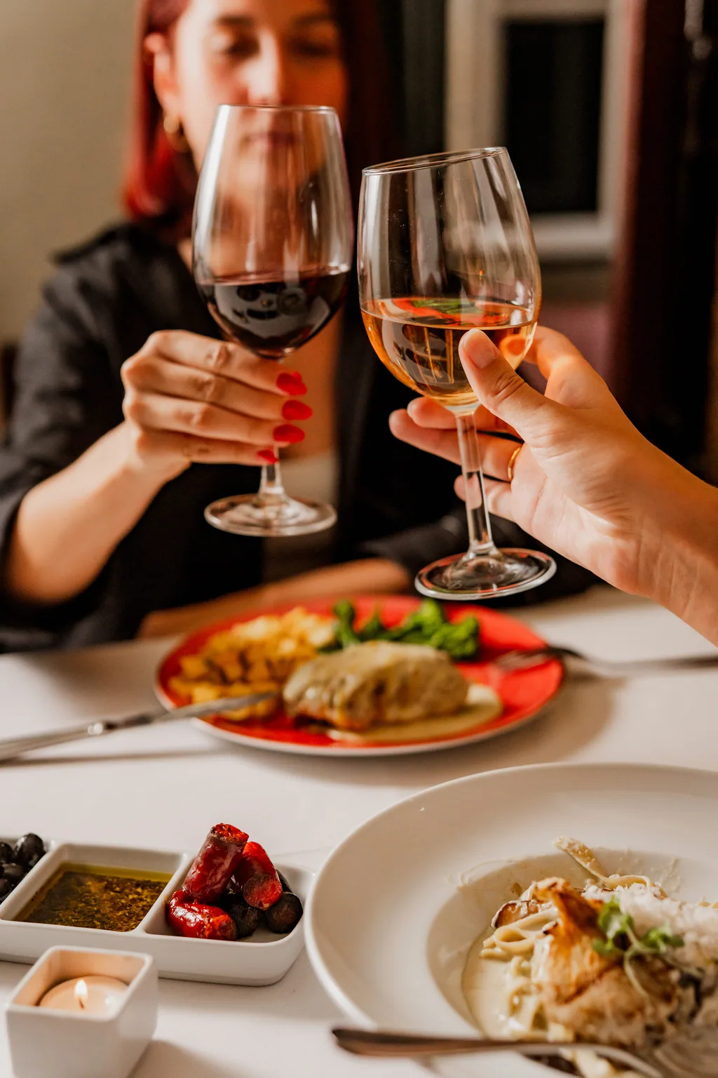 Anstoßen mit Rot- und Weißwein über dem Tisch