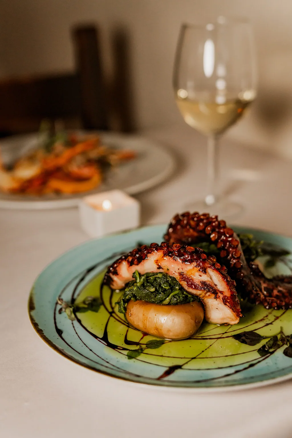 Oktopus nach Lagareiro-Art mit Stängelkohl auf grünem Teller