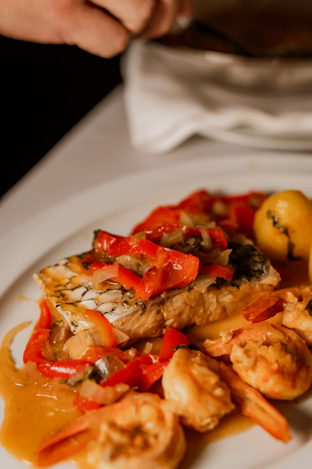 Peixe com pimentos e gambas em molho, na travessa