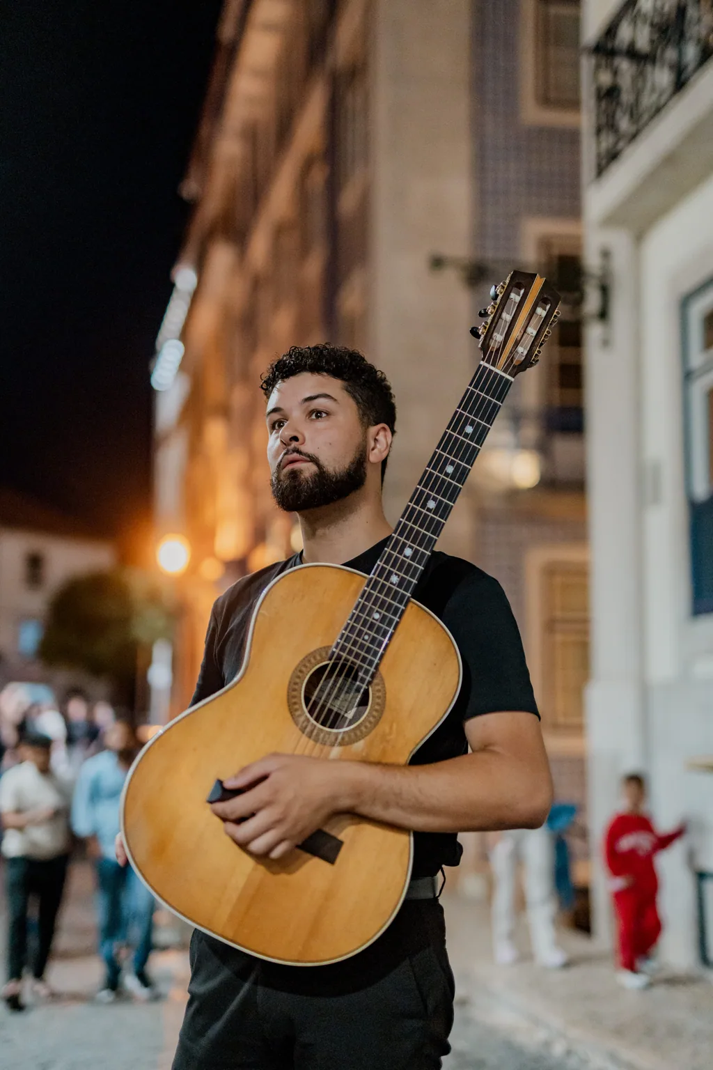 Junger Gitarrist bei Nacht in einer Gasse von Alfama