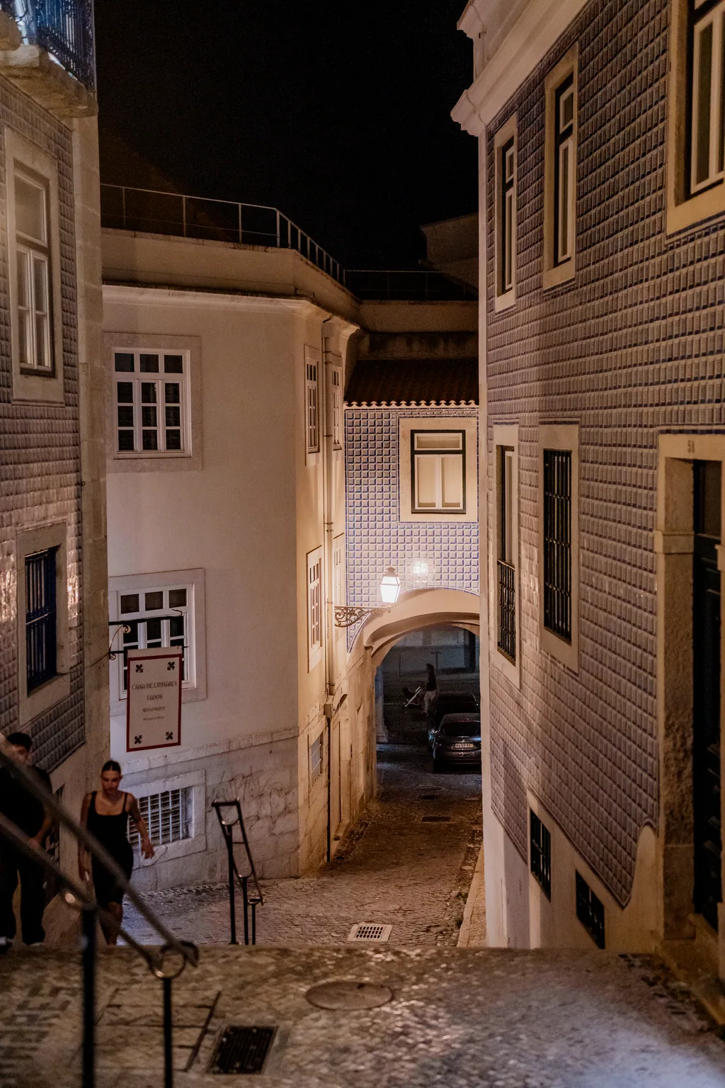 Narrow Alfama street at night, an archway at the end