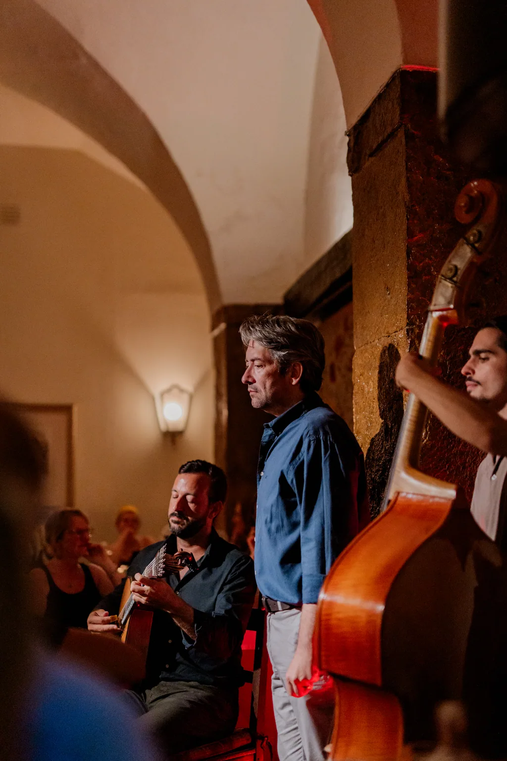 Double bass player standing beneath the arch, the room full