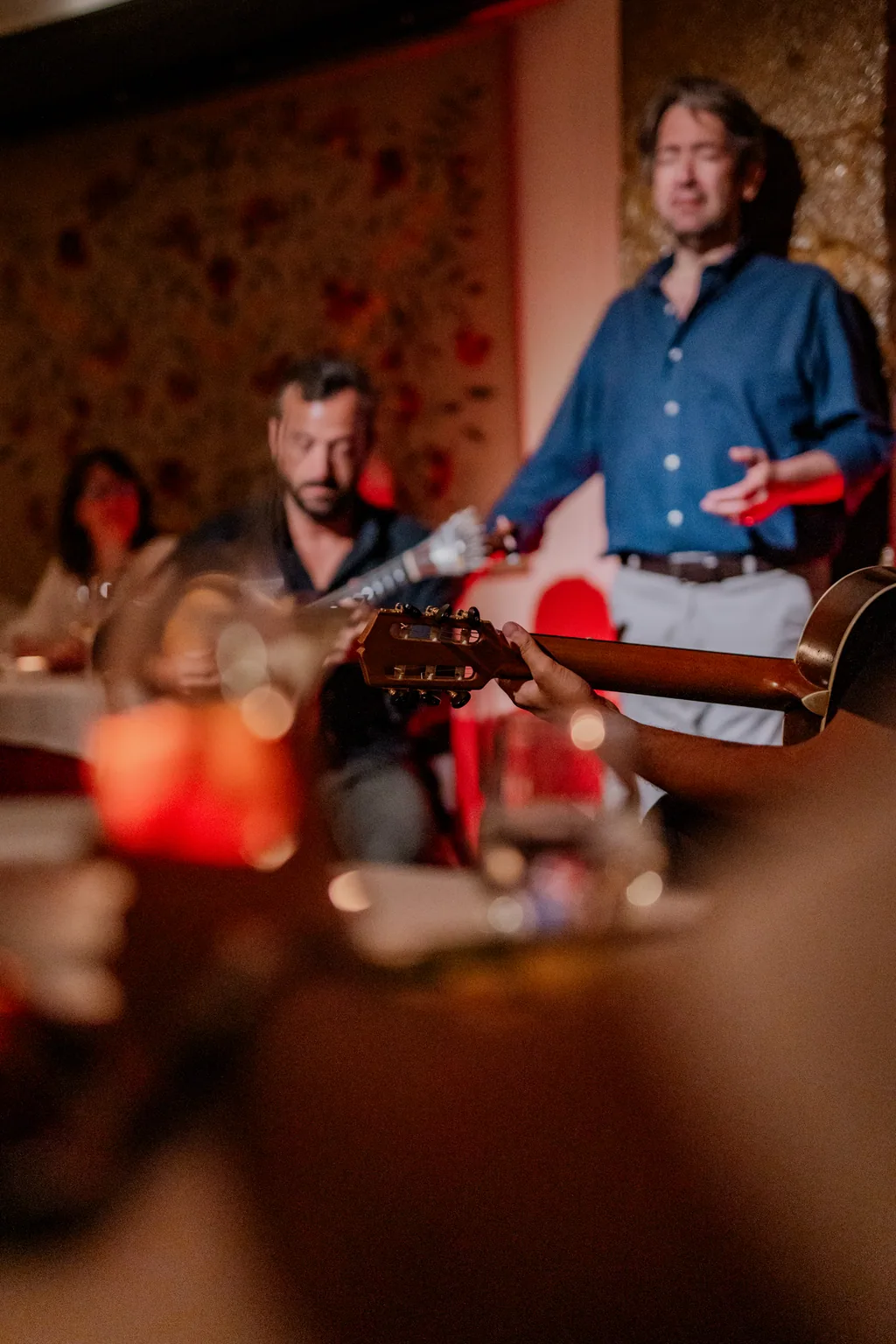 Fado singer performing, a wine glass blurred in the foreground