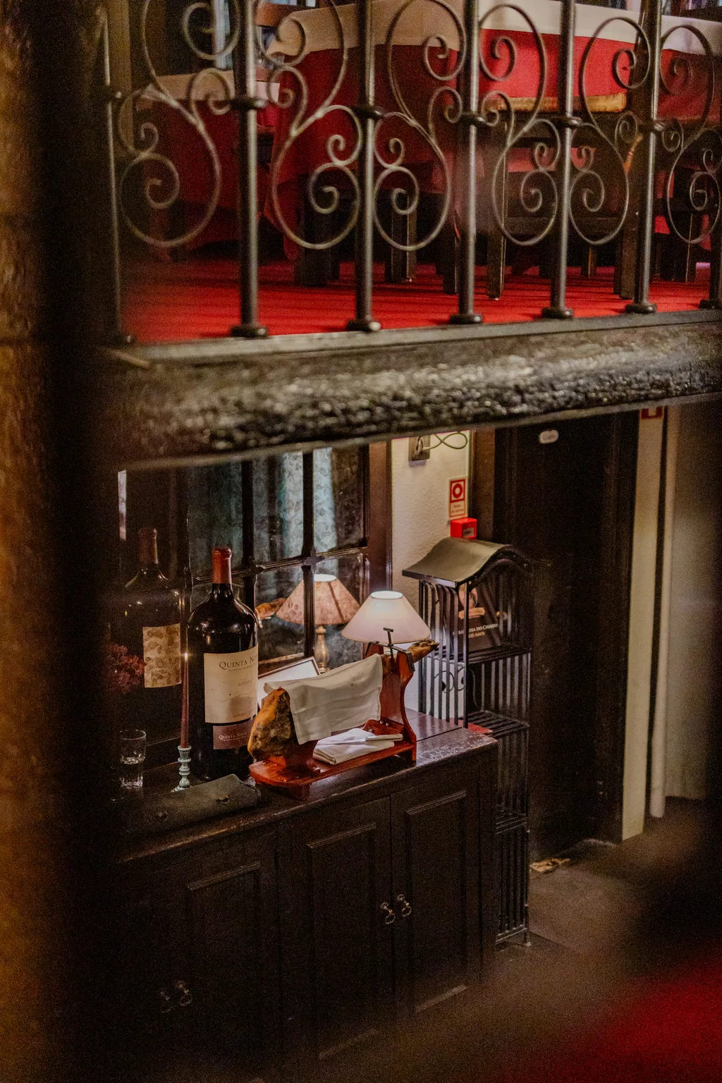 Old dresser with bottles and a lamp, beneath the wrought-iron balcony