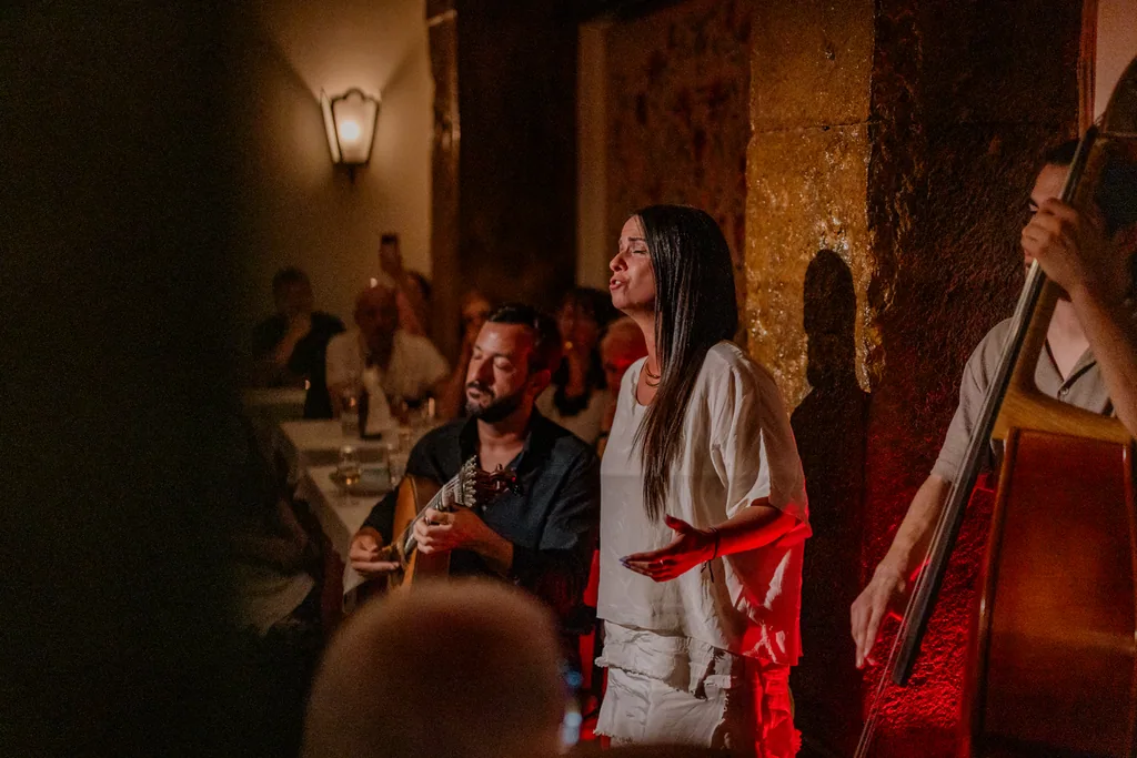 Fado singer in white with a red sash, the double bass behind
