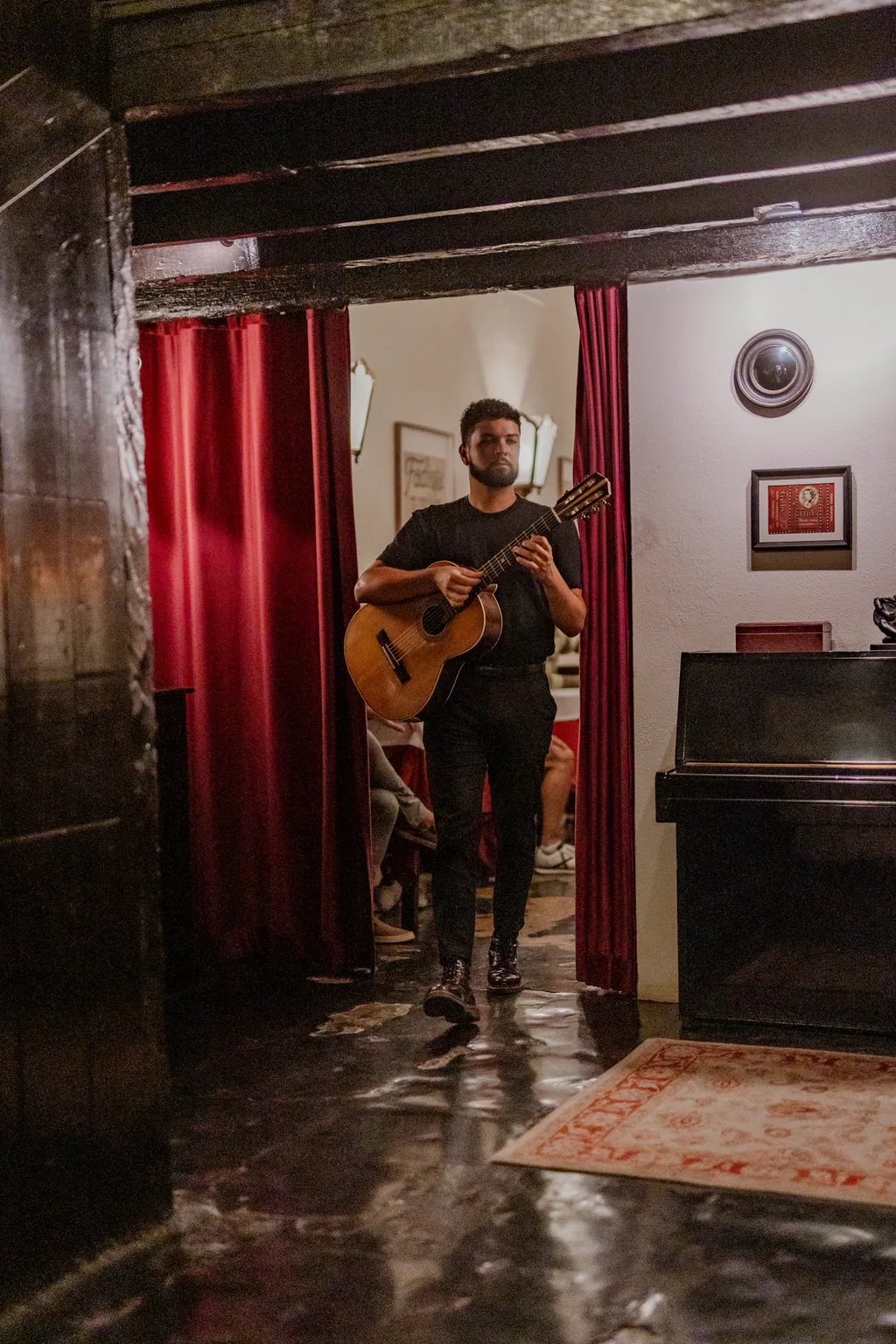 Guitarist stepping through the velvet curtain, the piano beside him