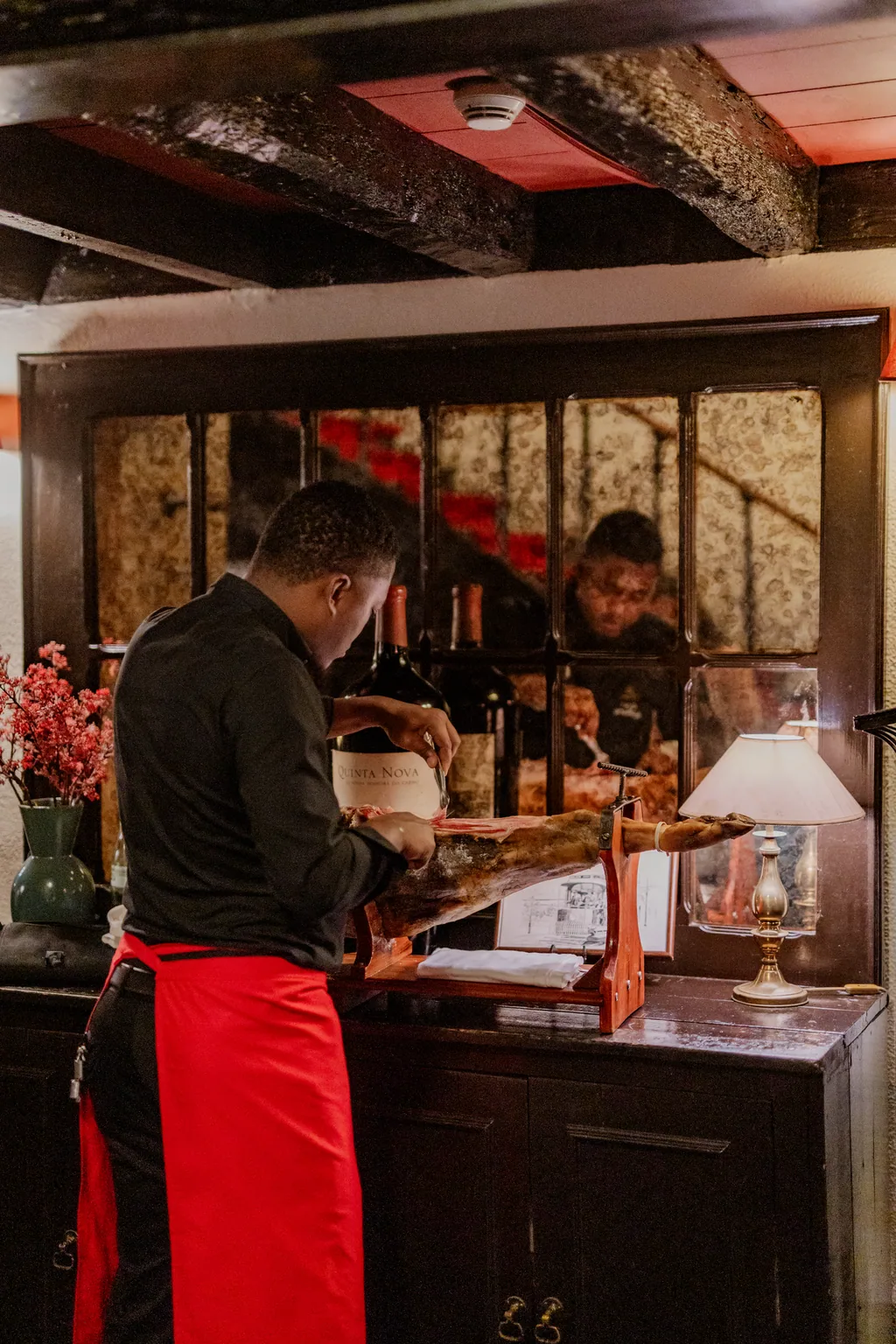 The ham being carved at the counter, in a red apron