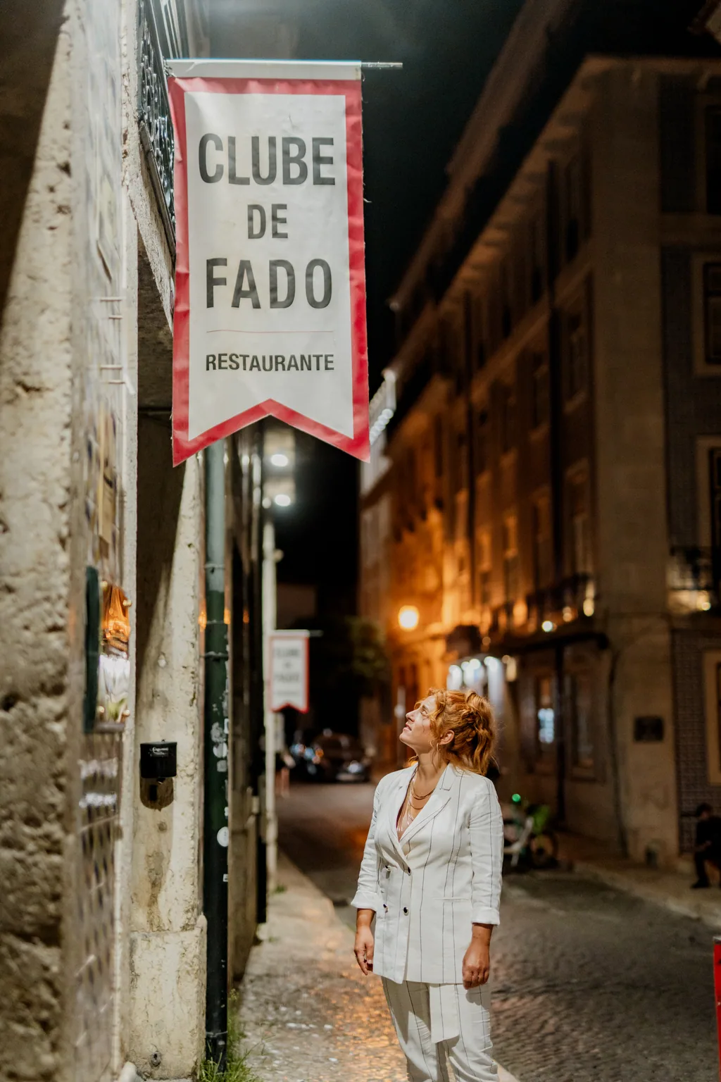 A flâmula iluminada na rua, com a fadista ao fundo